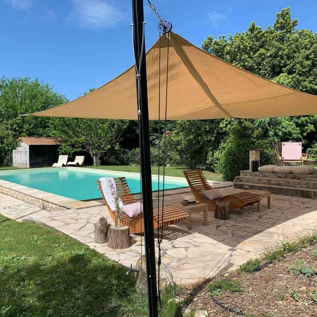 Voile d'ombrage avec son mat et système de tension sur une terrasse proche de la piscine