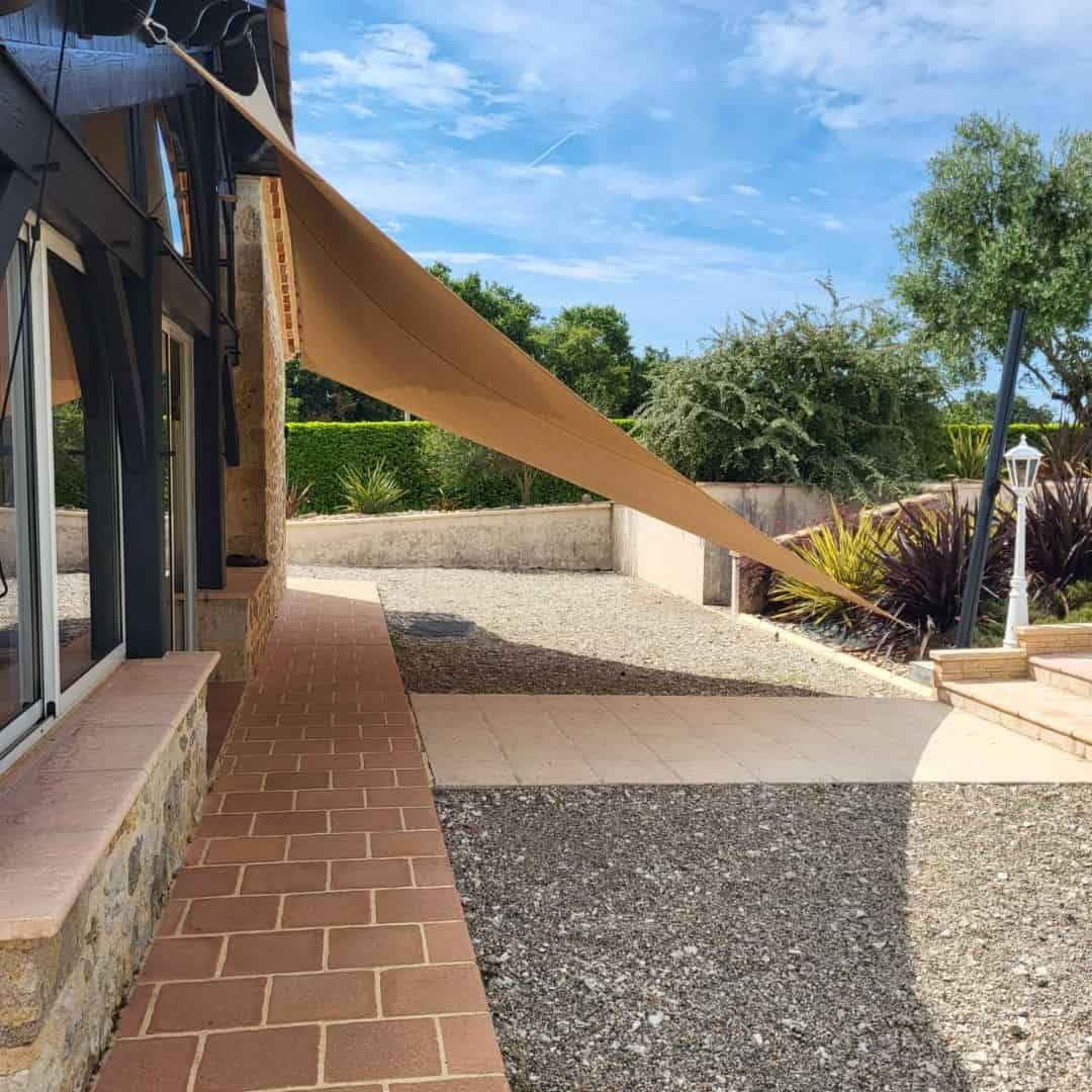 Voile ombrage ajouré servant de brise vue et brise vent sur une terrasse extérieure