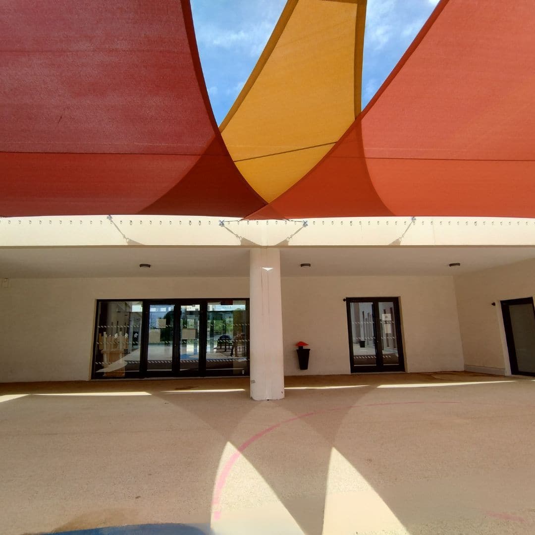 Voiles d'ombrage triangles multicolores pour ombrager patio et préau d'une maternelle